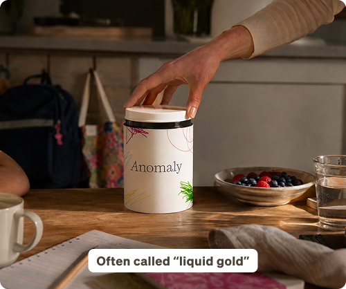 A jar of Anomaly supplement on a kitchen counter beside a bowl of fresh berries. Often called "liquid gold."