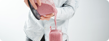 A physician in a white coat pouring a colostrum-based supplement drink into a glass jar.